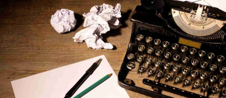 vintage typewriter on desk scrunched up paper pens