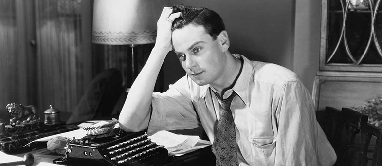 man looks frustrated leaning on typewriter black and white
